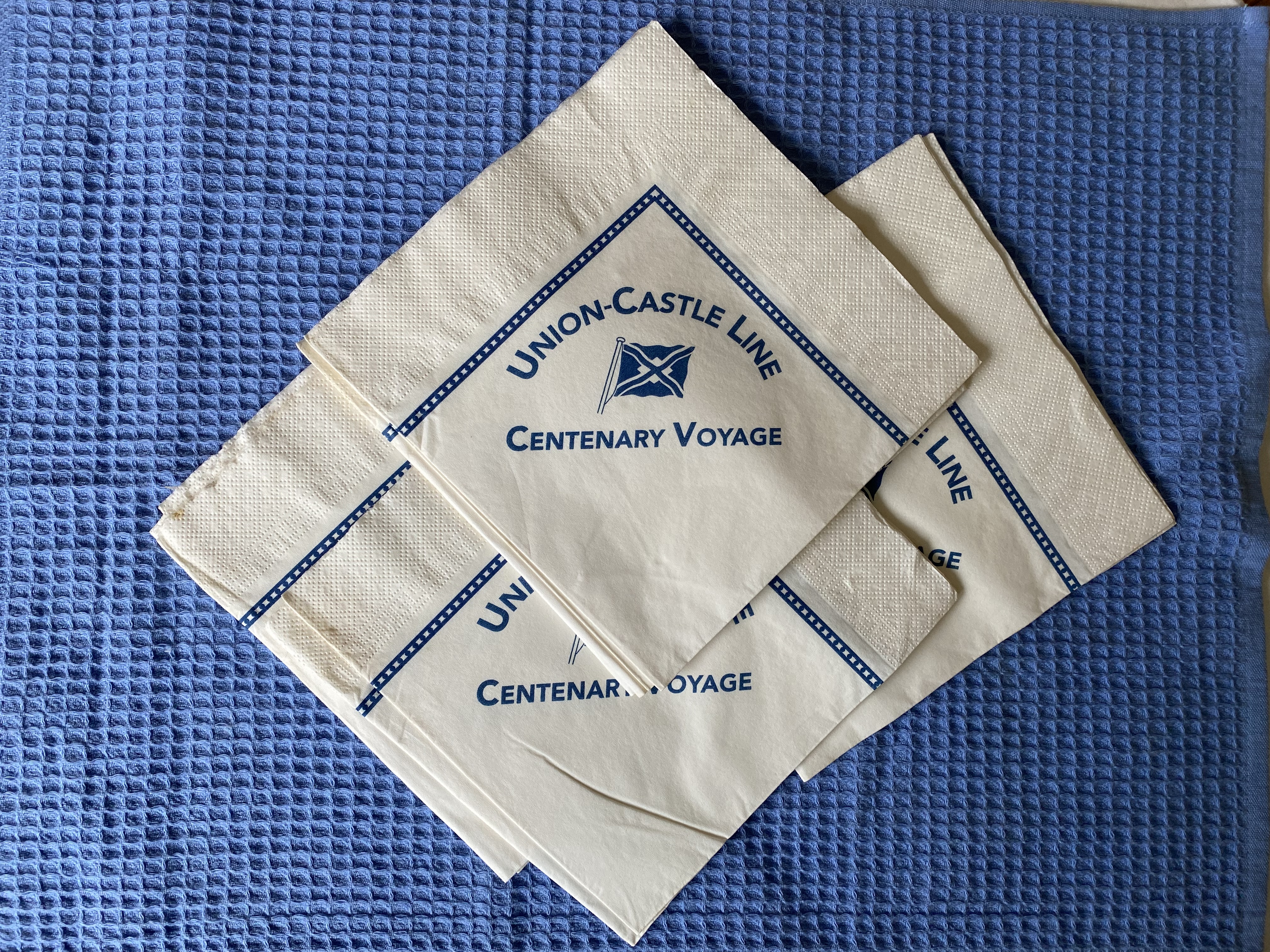 A PACK OF UNUSED PAPER TABLE NAPKINS FROM THE UNION CASTLE LINE CENTENARY VOYAGE ONBOARD THE VICTORIA